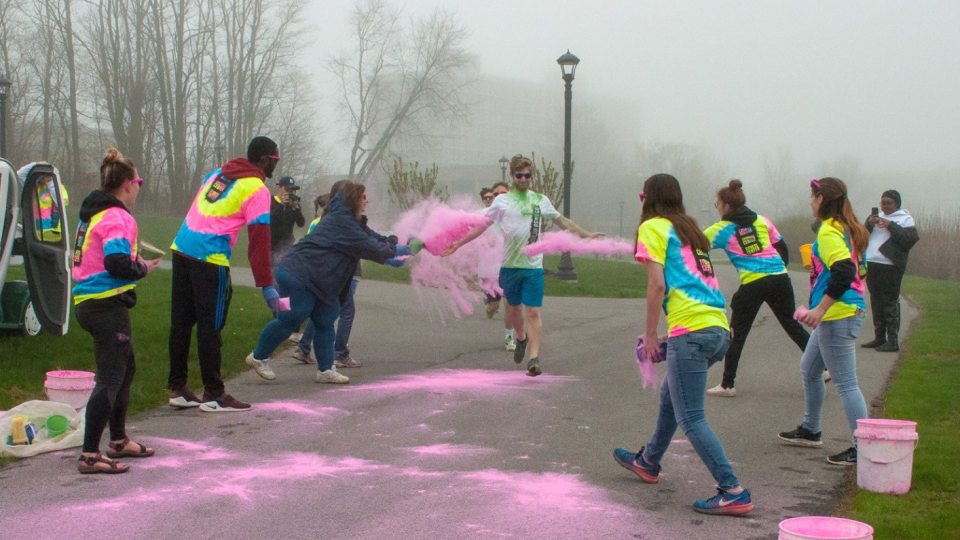 Volunteers throw powder on a color-run participant