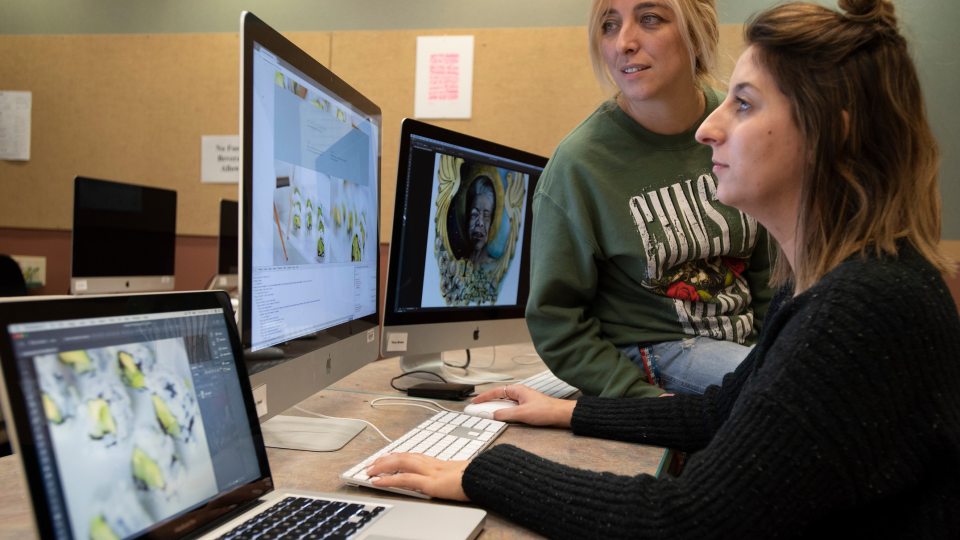 Two students work on digital images in a graphic design lab