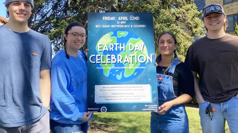 Four organizers of Earth Day activities hold up a poster