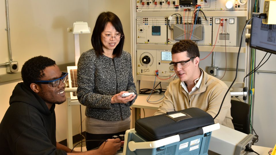 ECE faculty member Hui Zhang (standing), works with students (from left) Chibuike Ogbonna and Avery Croucher in spring 2022, after earning National Science Foundation funding for research related to improving the charging of electric vehicles.
