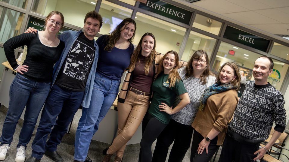 Staff and student members of the Experiential Learning office stand in front of the Compass in Marano Campus Center, where their offices are located.