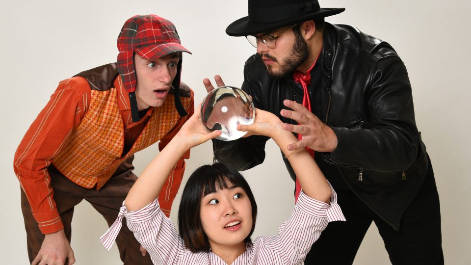 Rehearsal image of performers trying to discern the future via a crystal ball