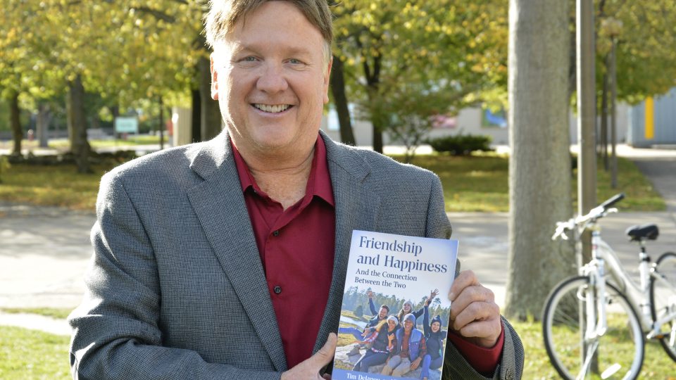 Tim Delaney with a book and fall foliage as a backdrop