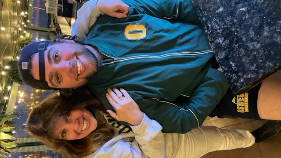 Annie and Ryan at restaurant in SUNY Oswego gear