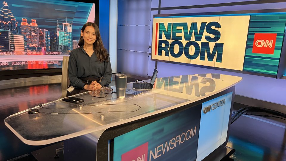 SUNY Oswego student Clarissa Karki sitting at the CNN newsroom anchor desk.