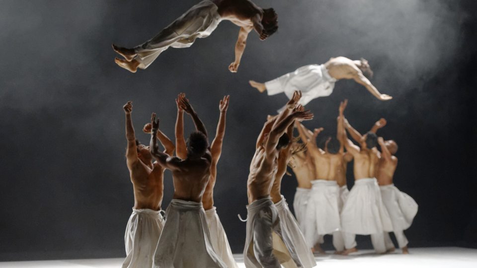 Dancers soar in the air as groups of fellow troupe member wait to catch them