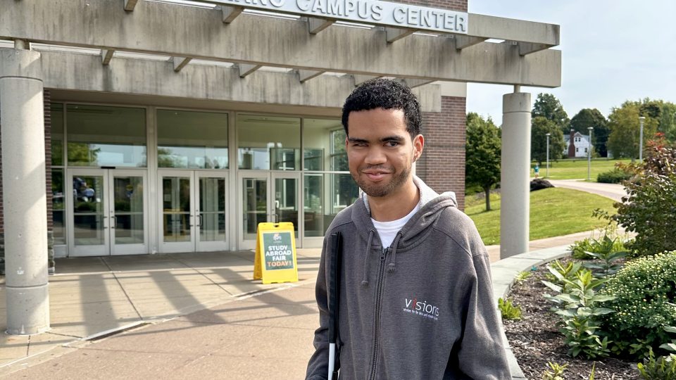 Student Luis Perez-Rivera stands outside in front of the Marano Campus Center wearing a grey hoodie.