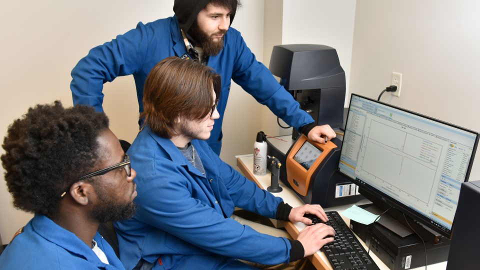 Student researchers (from left) Clinton Adu, Blake Britton and Muhammad Musozoda examine data.