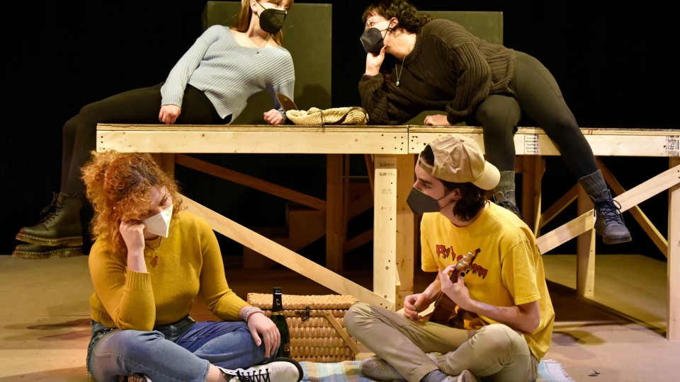 Four theatre students rehearse in two rows having two conversations