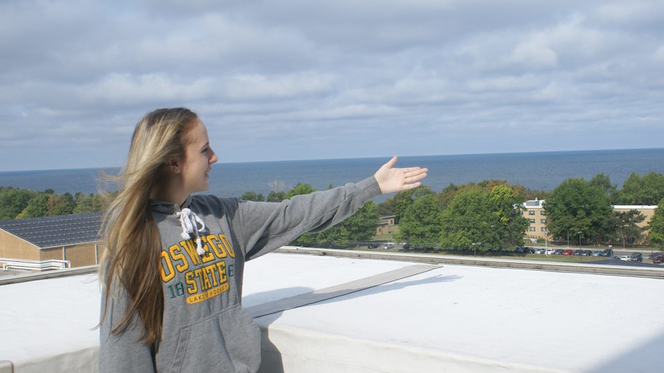 Student tour guide gestures and lake and campus