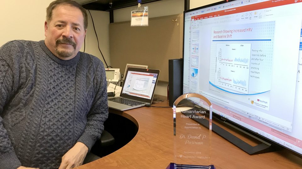 David Parisian with award and screen with data