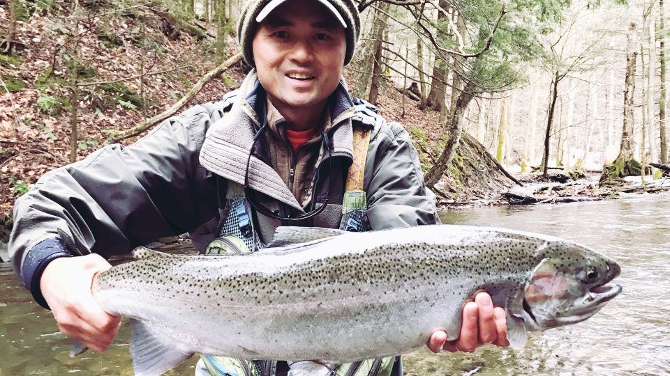 Michael Huynh holding a large fish while standing in a river