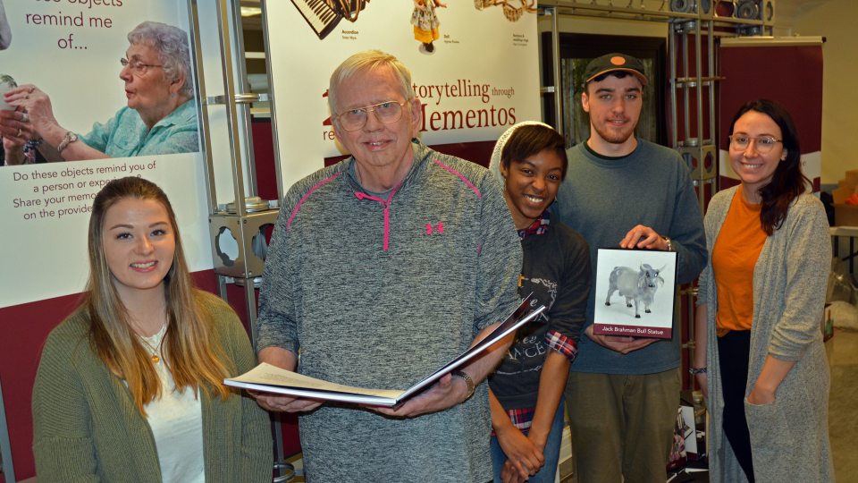 Students and a senior citizen with items from Recollections art exhibition