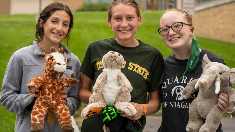 Three students hold up stuffed animals they assembled during 2021 Rec the Night new-student welcoming activity