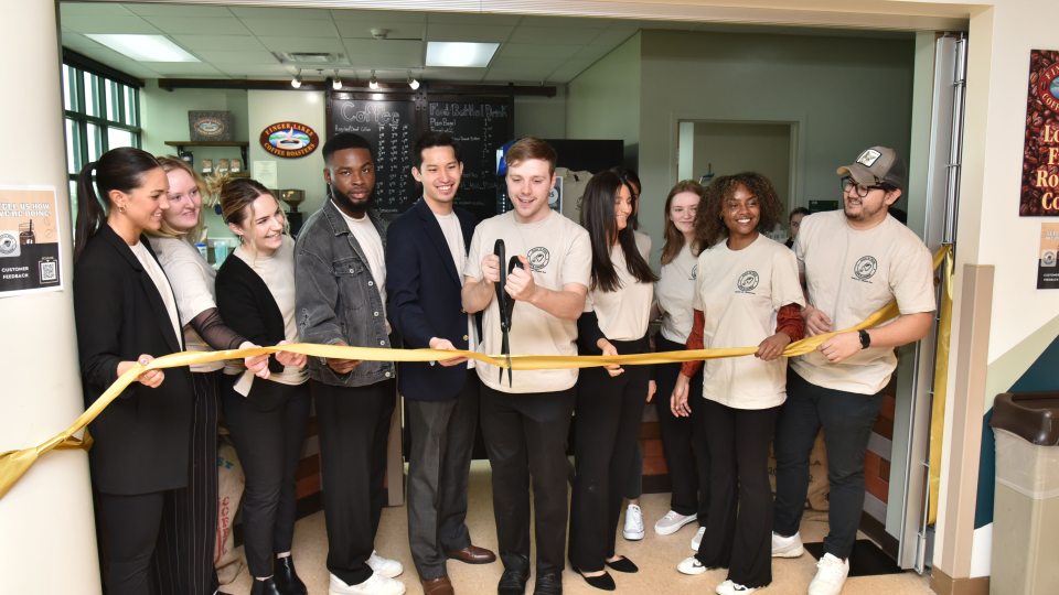 Students in SUNY Oswego’s Management 444 class hold a ribbon-cutting ceremony during an April 11 grand opening for the new Rich N’ Pour Cafe in the Rich Hall lobby.