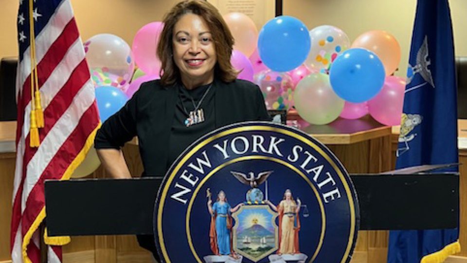 Maggie Rivera posing behind the senatorial seal during an awards ceremony