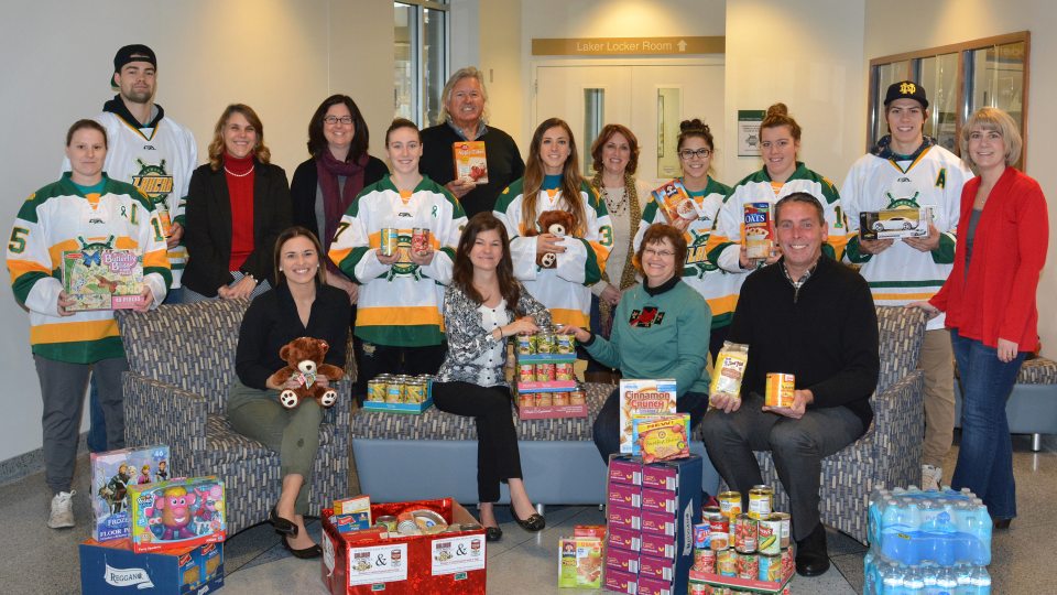 Hockey players, Oswego employees, and representatives of United Way and Human Concerns Center with food and toys