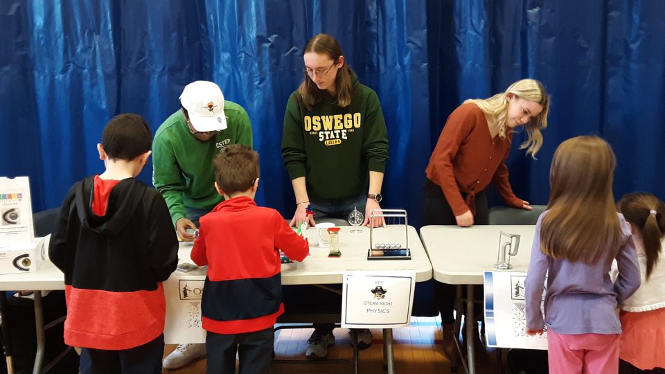 SUNY Oswego students Daniel Thomas, Hugh Riley Randall and Layla Sprague help elementary school students with a STEAM activity