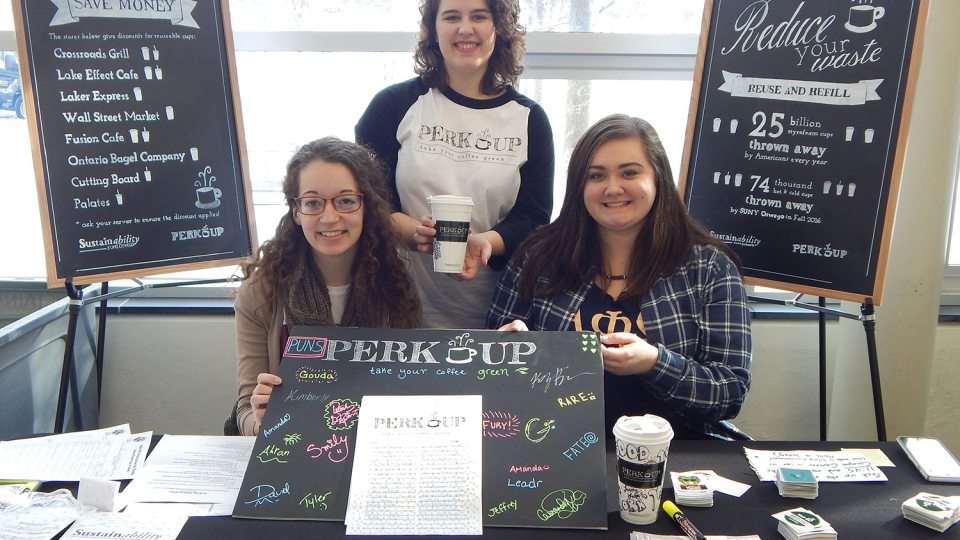 Students showing off Perk Up program to promote refillable coffee mugs