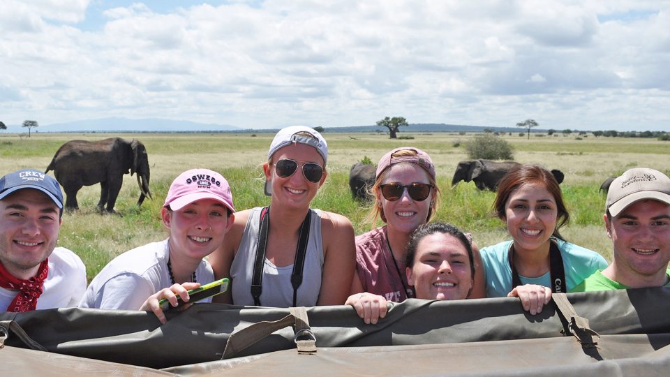 Students pose with elephants in background