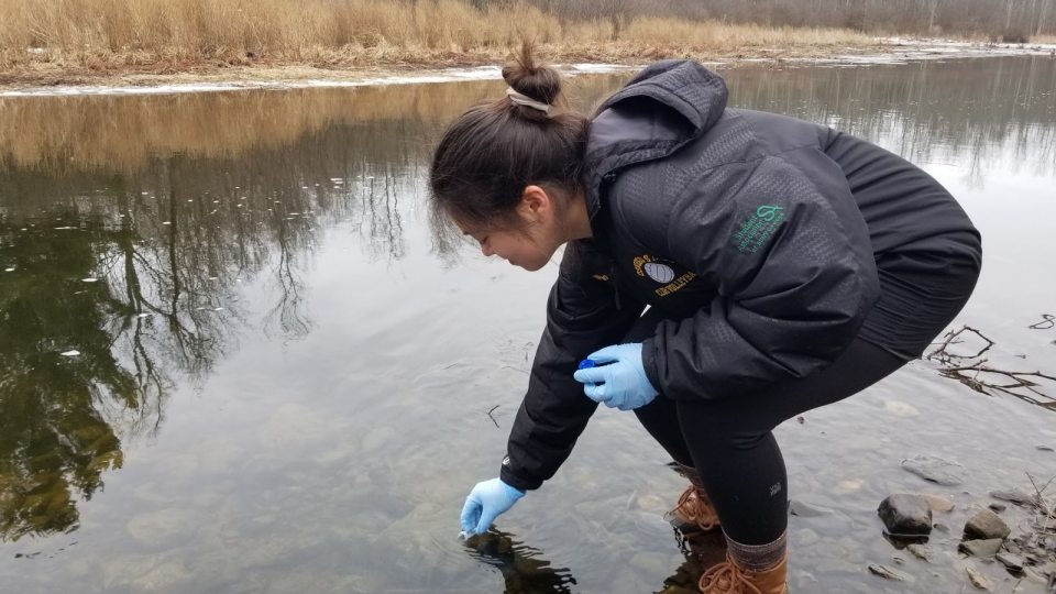 Sydney Waloven collects water samples for a research study