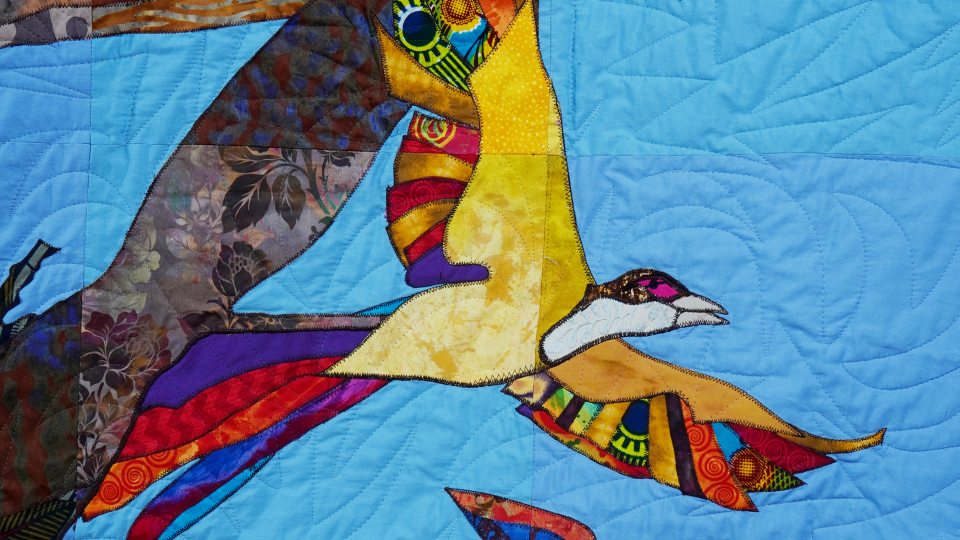 A multicolor community-created quilt that uses birds as a metaphor for the Black experience in America