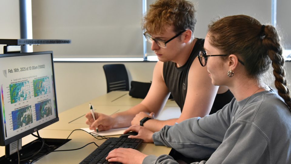 Tom White and Zoe Bush, who just earned their meteorology degrees in May, look over data from their research with Climavision related to gap-filling radar
