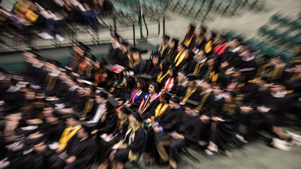 commencement photo of students sitting in their chairs that is half blurred