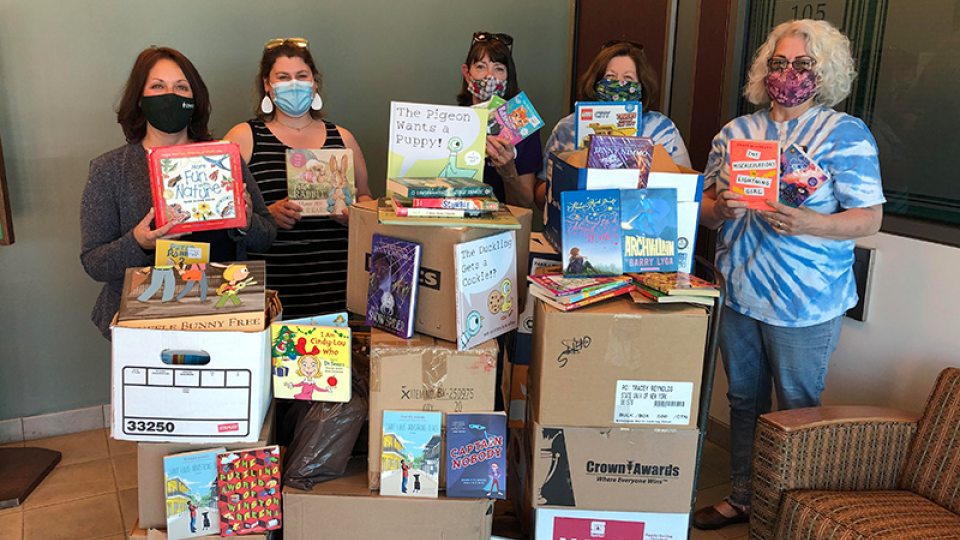 College participants and Oswego Bookmobile volunteers show off some of the hundreds of books donated to the local cause