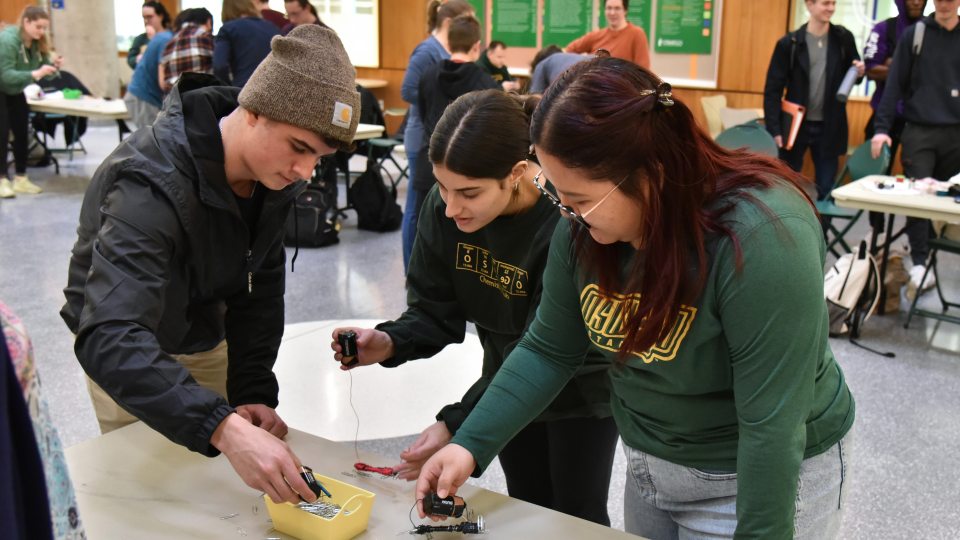 Three students work on an electromagnetism competition at a previous Engineering Week