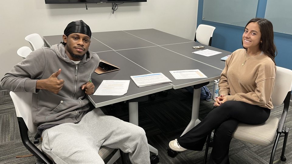 Two SUNY Oswego Empire State Service Corps students, Malik Hills and Izzy Ronacher, staff a walk-in session for students to apply for Supplemental Nutrition Assistance Program benefits in the Educational Opportunity Program Office in Penfield Library.