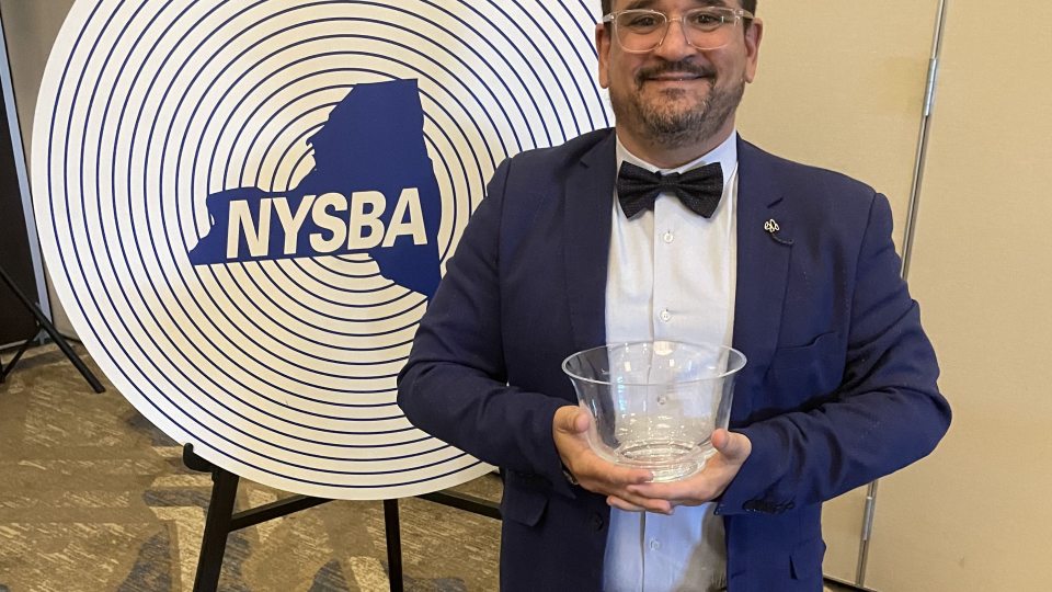 Francisco Suarez, associate professor in the communications department, poses with his trophy at the New York State Broadcasting Association awards ceremony.