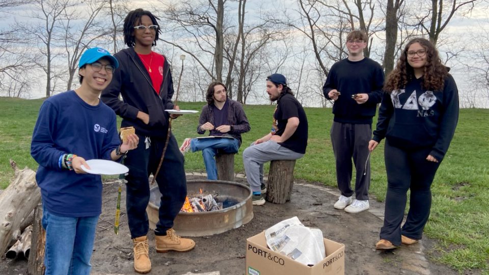 Great Lakes Institute interns and student volunteers with Shining Waters lakeshore cleanup pause during a post-pickup bonfire