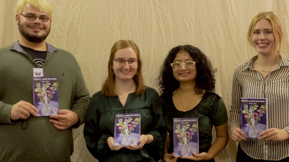 Students with Great Lake Review hold a previous edition of the magazine during a release party at the River's End Bookstore