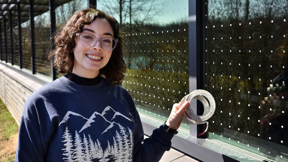 Senior zoology major Brooke Goodman shows off some of the window stickers at Rice Creek that serve as deterrents for birds