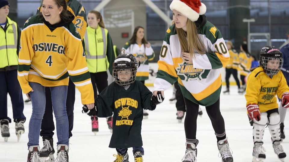 Laker women's hockey players skating with children