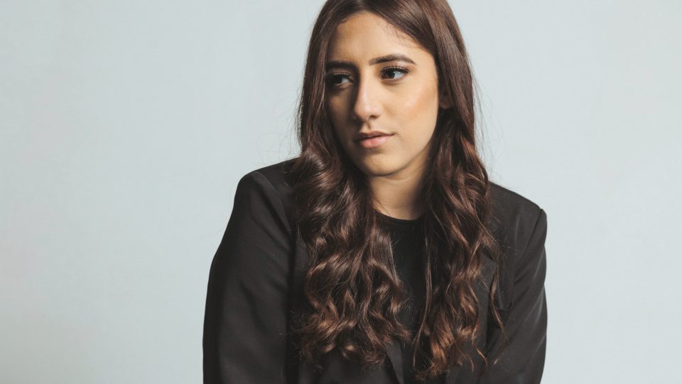 SUNY Oswego student Isanere Nunez poses for a professional photo in front of a light blue background.