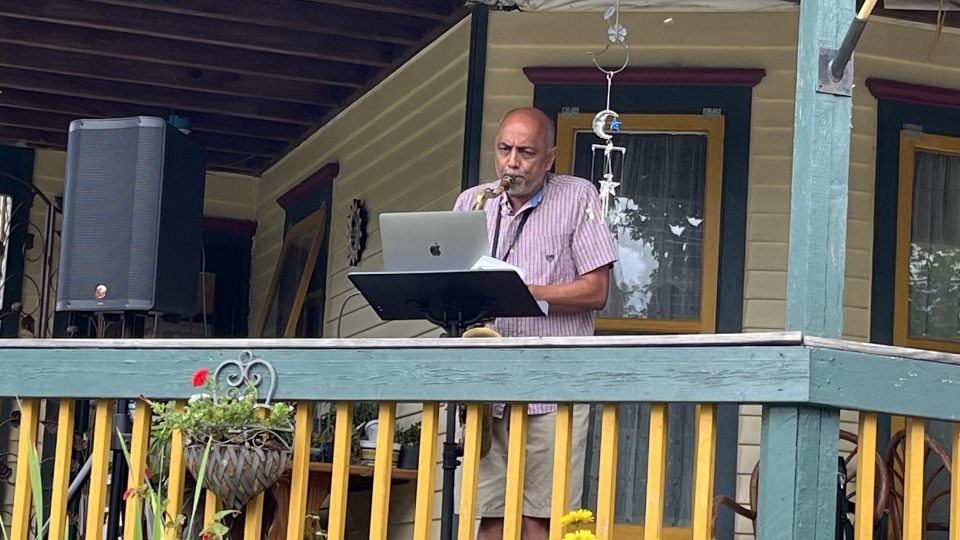 Shashi Kanbur plays the saxophone on a porch