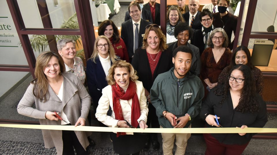 Members of the college community cut a ribbon to symbolize the opening of the SUNY Oswego Institute for Equity, Diversity, Inclusion, and Transformative Practice in Penfield Library