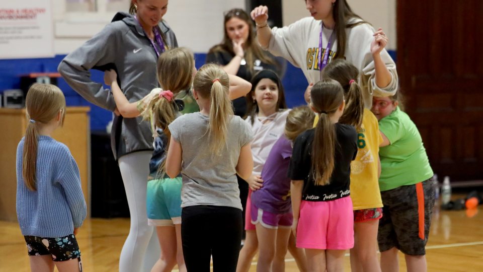 Two members of the Laker women's basketball team enjoy working with girls in the Her Time To Play program at the Oswego YMCA