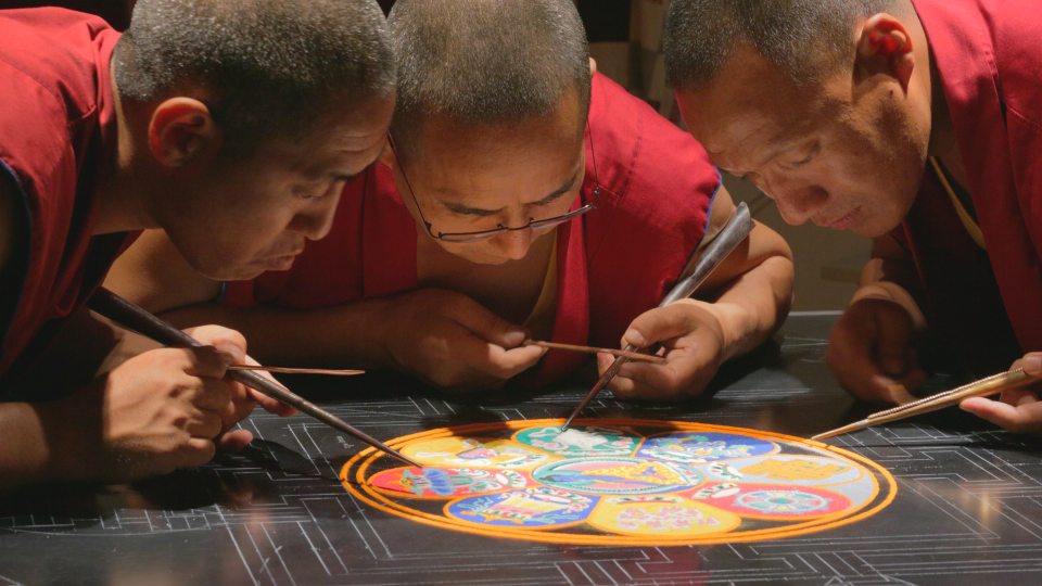 Monks work on creating mandala, beautiful sand art