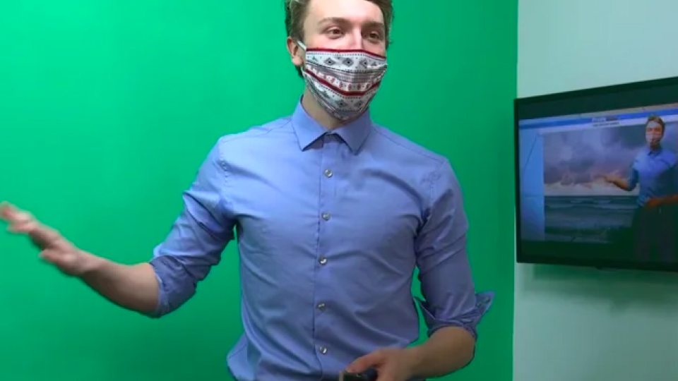 Daniel Maslowski gives a weather forecast in front of a green screen in the Shineman Center