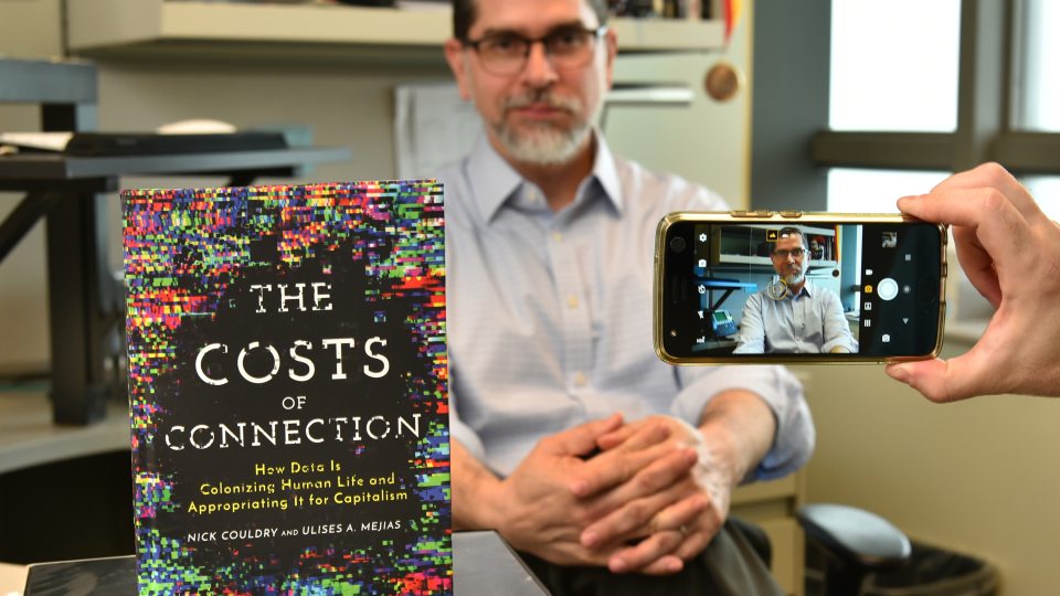 Ulises Mejias, as viewed through a smartphone, with his new book about the harvesting of online data