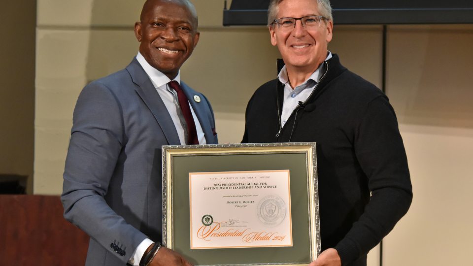 PHOTO CAPTION: SUNY Oswego President Peter O. Nwosu (left) presents Bob Moritz, Class of 1985, with the prestigious Presidential Medal during the inaugural Sheldon Lecture on Sept. 24.