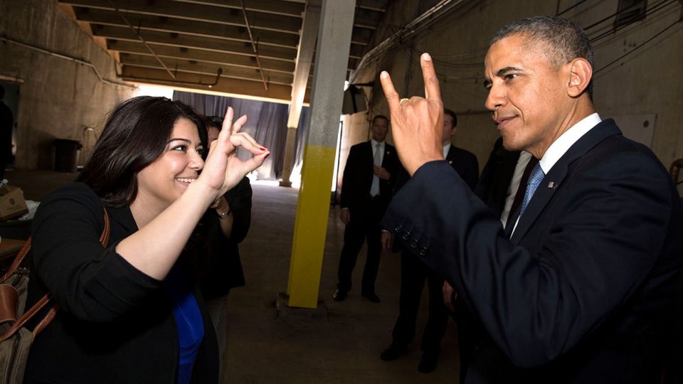 President Barack Obama's Personal Secretary Ferial Govashiri shows him how to make the sign of the anteater, mascot of the University of California, Irvine, prior to the UCI commencement at Angels Stadium in Anaheim, Calif., Saturday, June 14, 2014.
