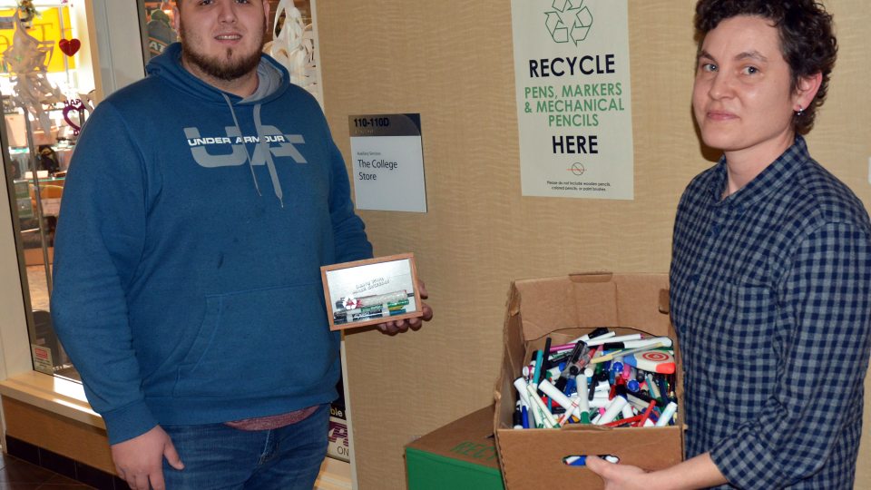 Kate Spector and student assistant Connor Haney prepare to feed used writing implements to a TerraCycle zero waste recycling box