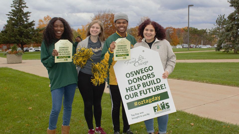 Students hold sign promoting tag day recognizing the importance of donors