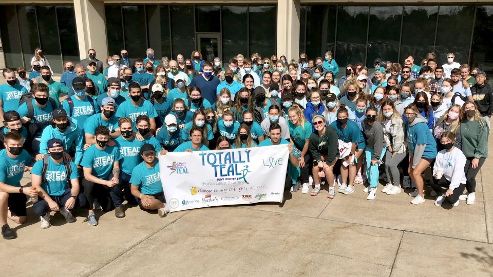 SUNY Oswego campus community members in a group wearing teal