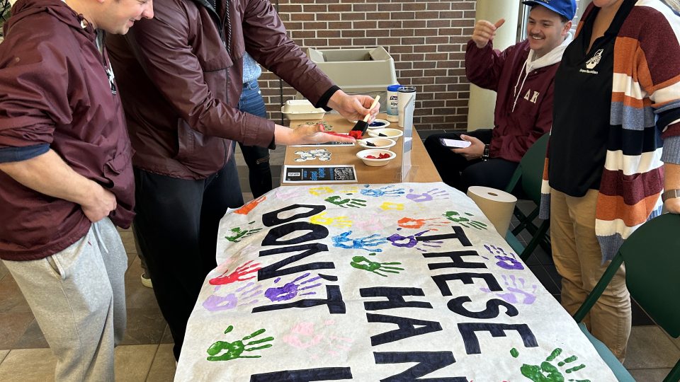 Students sign These Hands Don't Haze banner