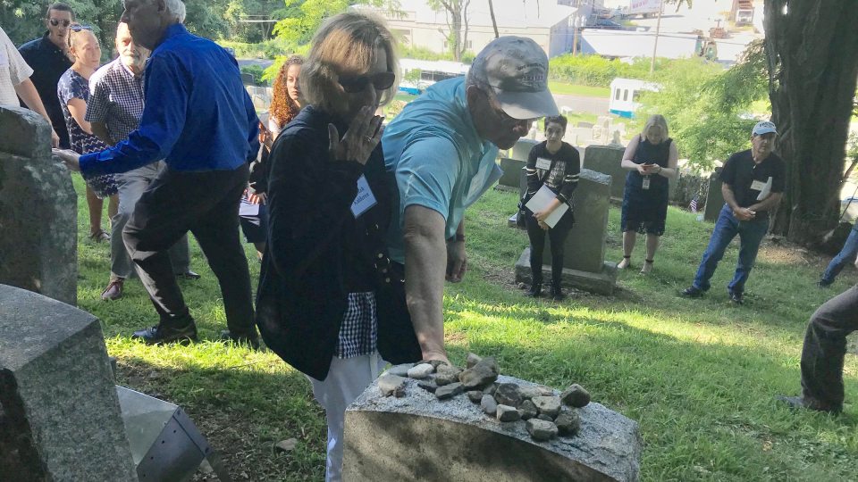 Former European refugees and families walk through a cemetery in Fort Ontario
